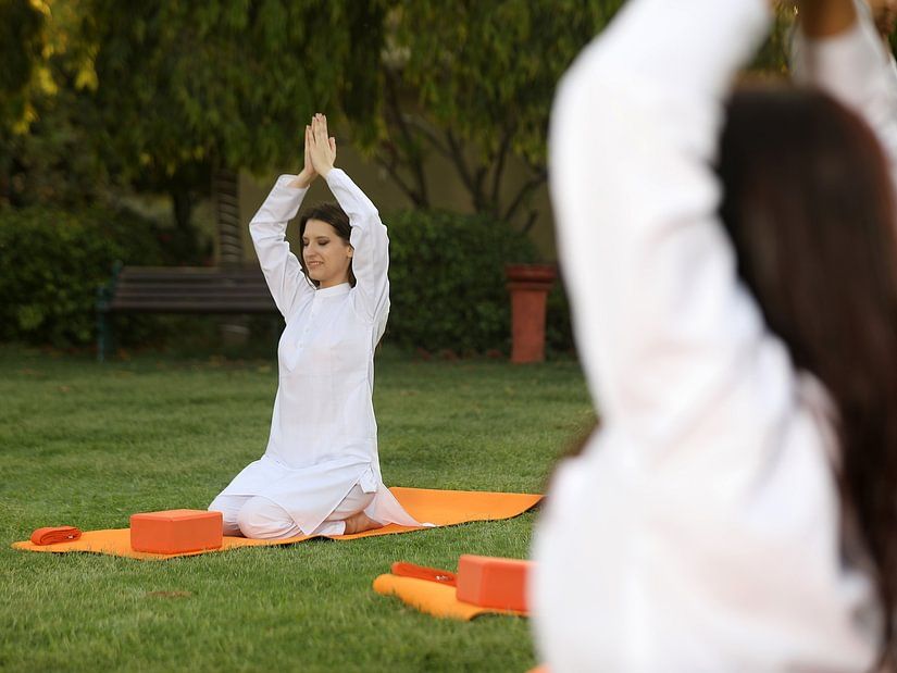 two women in namaste pose on lawn