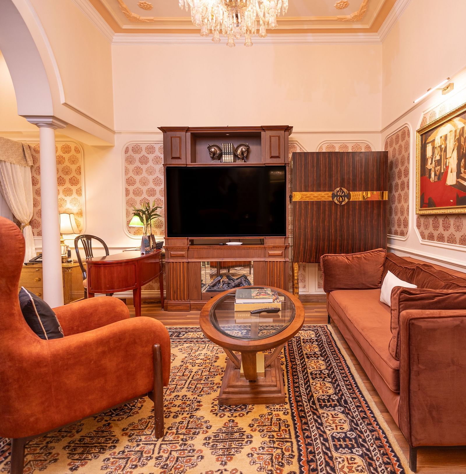 Executive Suite at The Claridges New Delhi, featuring a cosy sofa and corner chair beneath a chandelier