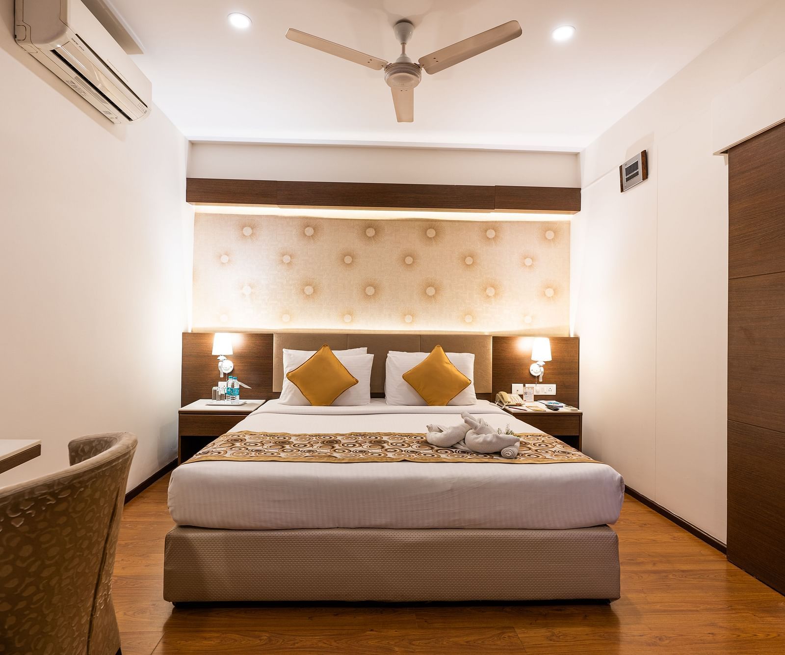 a double bed with a fan hung above and an ac wall mounted next to it inside one of the rooms - Hotel Pai Vista, Mysore