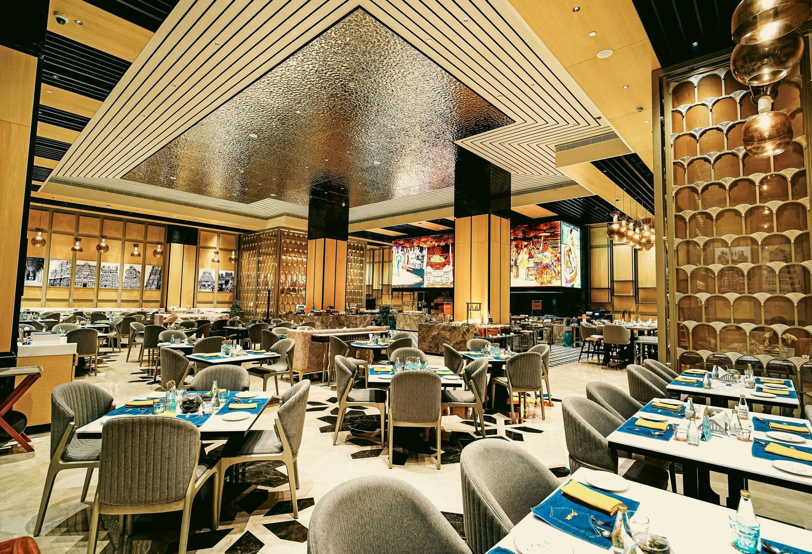 A wide view of the vibrant restaurant interior with elegant dining tables and unique ceiling design - Grand Madurai by GRT Hotels