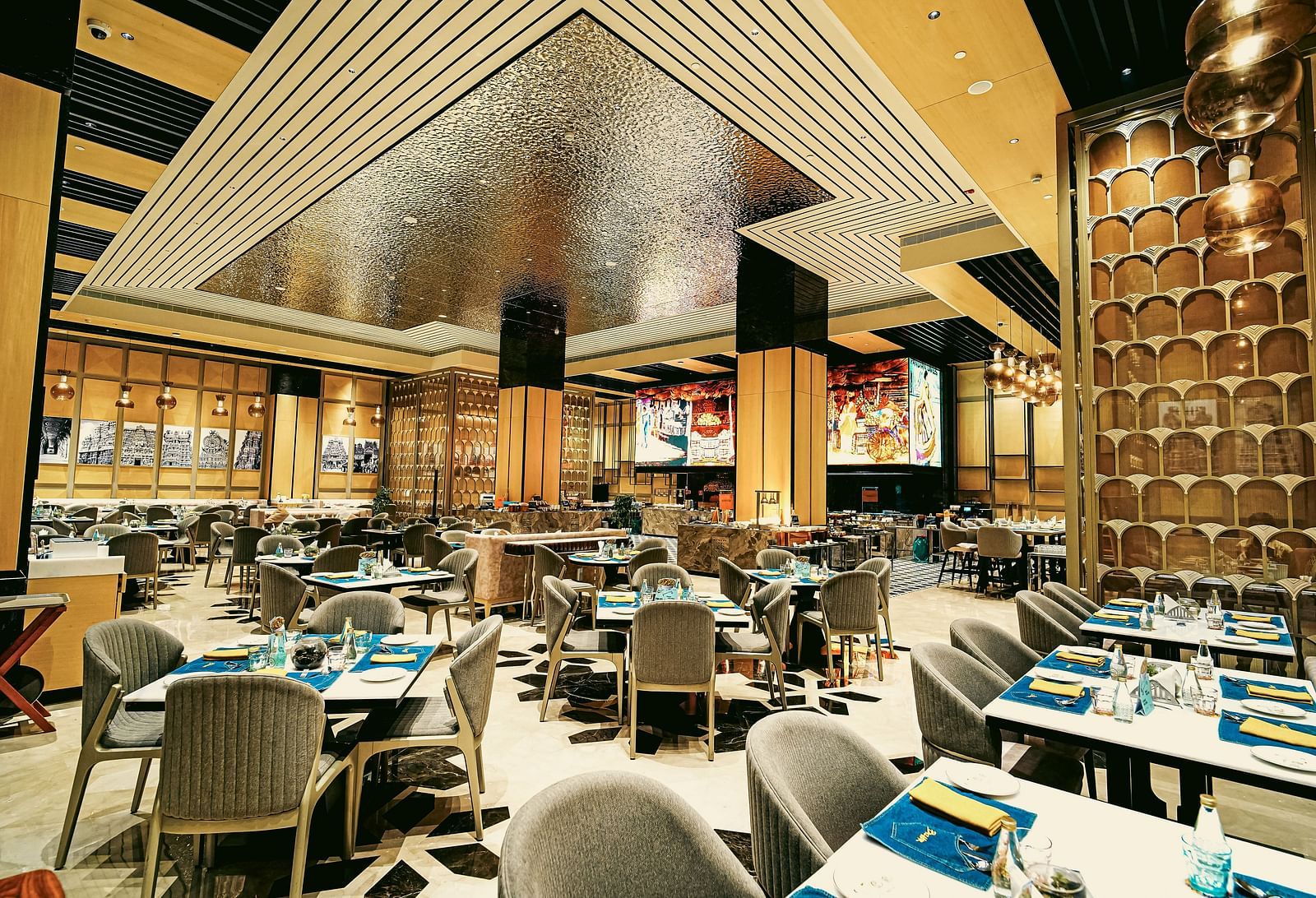 A wide view of the vibrant restaurant interior with elegant dining tables and unique ceiling design