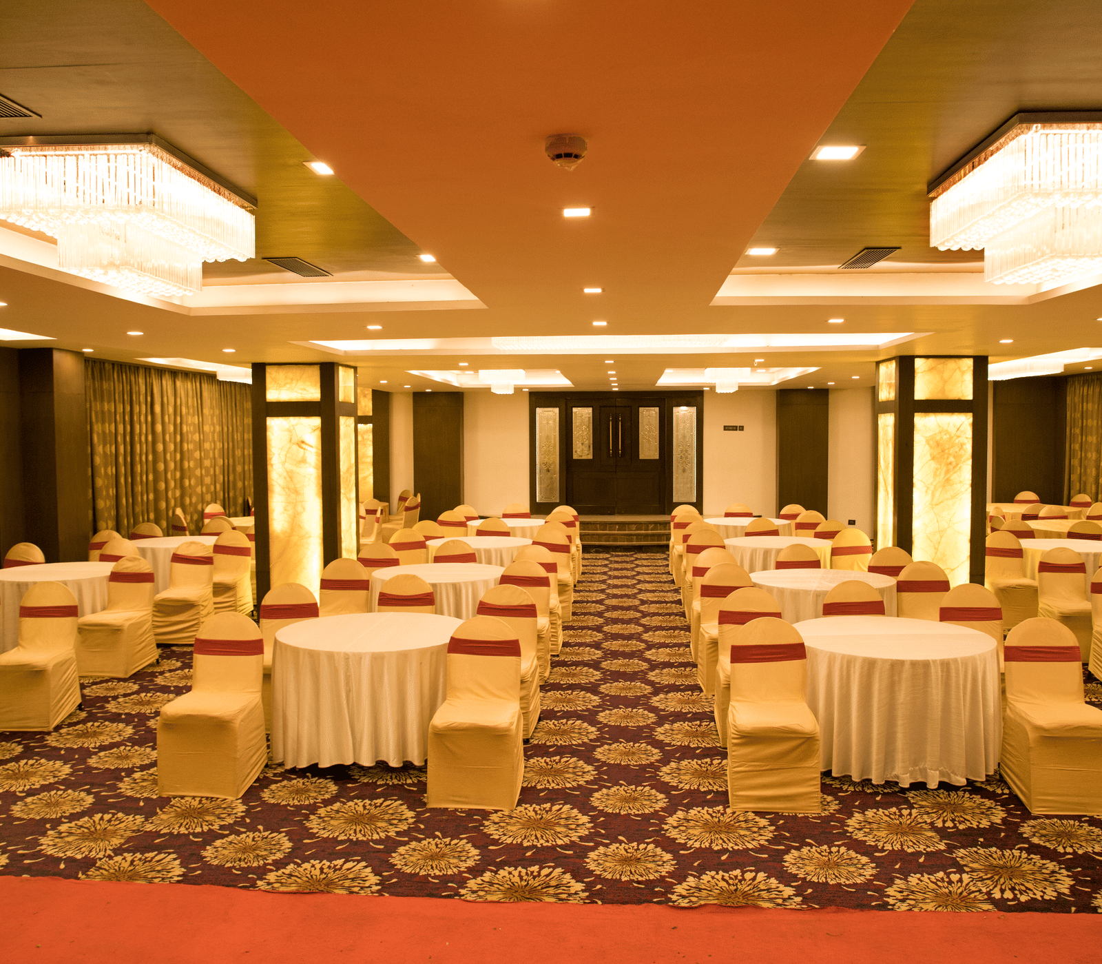 A banquet hall at Benzz Park Chennai set up with round tables and chairs with white covers, ready for an event.