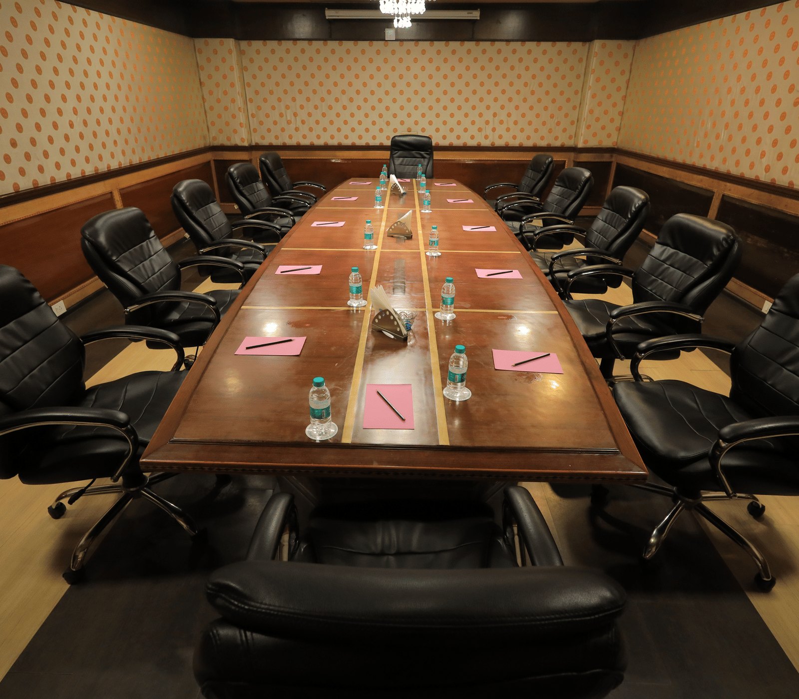The boardroom at Benzz Park, Vellore featuring a wooden conference table lined with black cushioned office chairs.