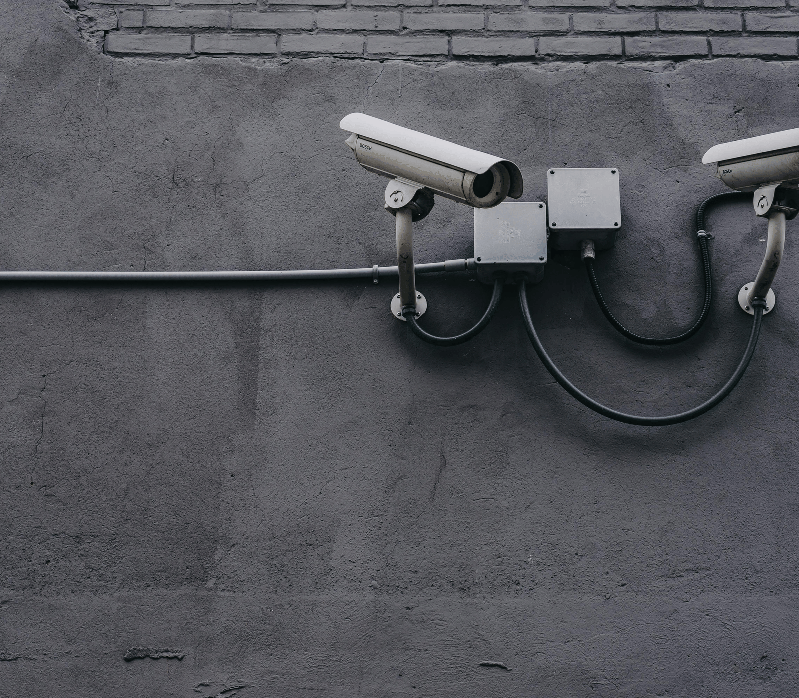 Wall-mounted CCTV cameras fixed on a grey exterior wall.