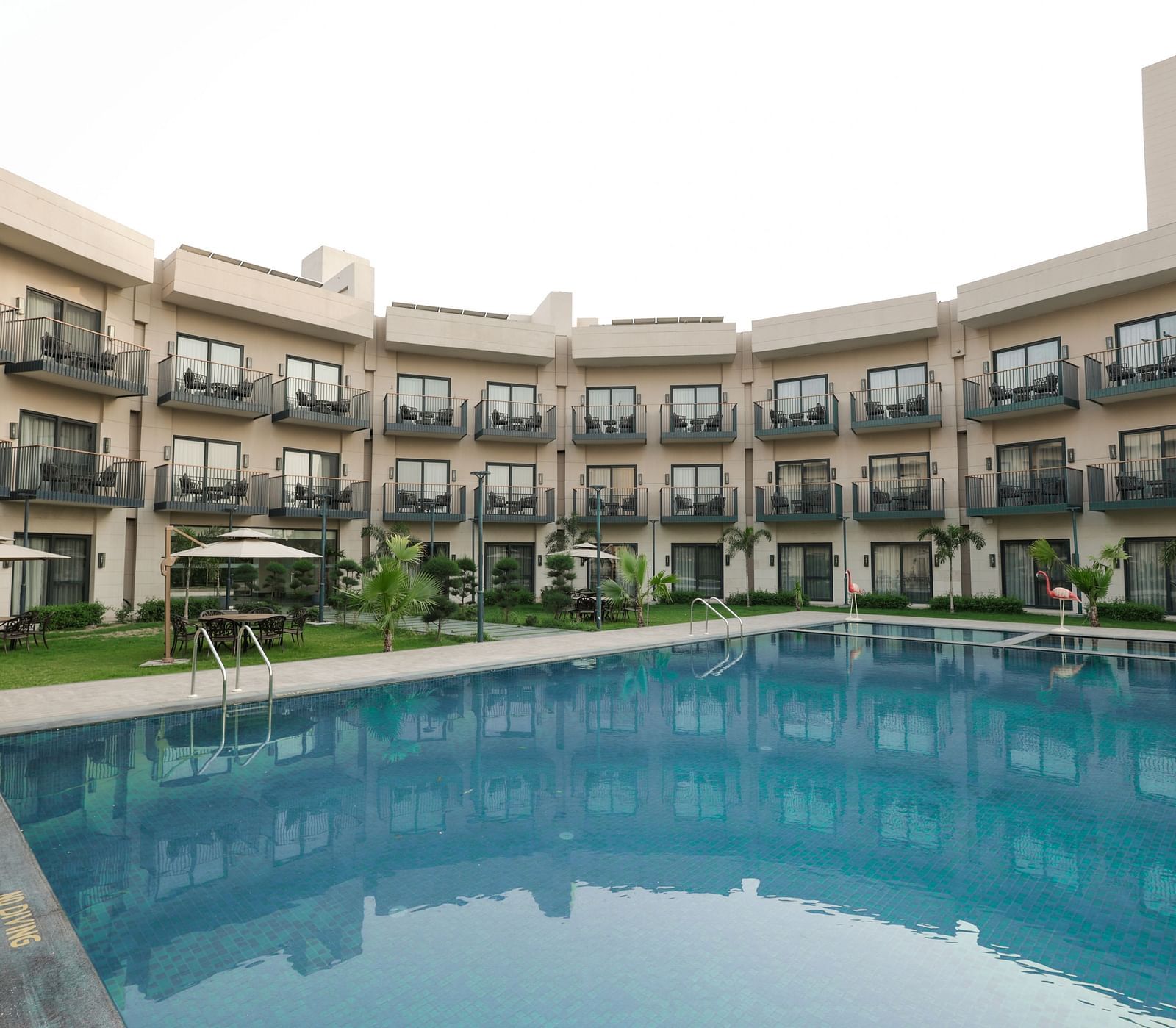 Poolside view of the hotel's courtyard and room balconies at Ramada by Wyndham Sonipat Murthal