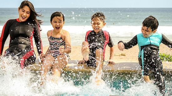 Image of a women and few kids playing in water and beach in the background