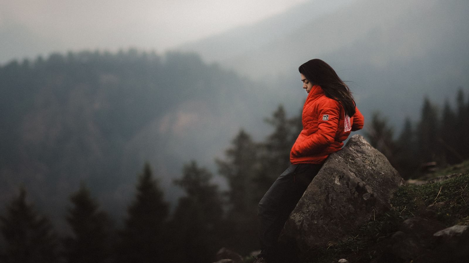 a solo woman traveller posing for a picture on top of mountain