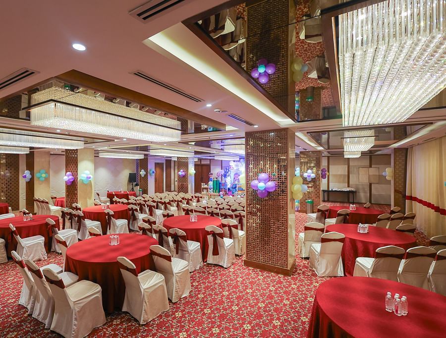 Side view of Blossom hall with stylish decor, lights, and round seating at Icon Premier Hotel by Bhagini, Devarabisanahalli