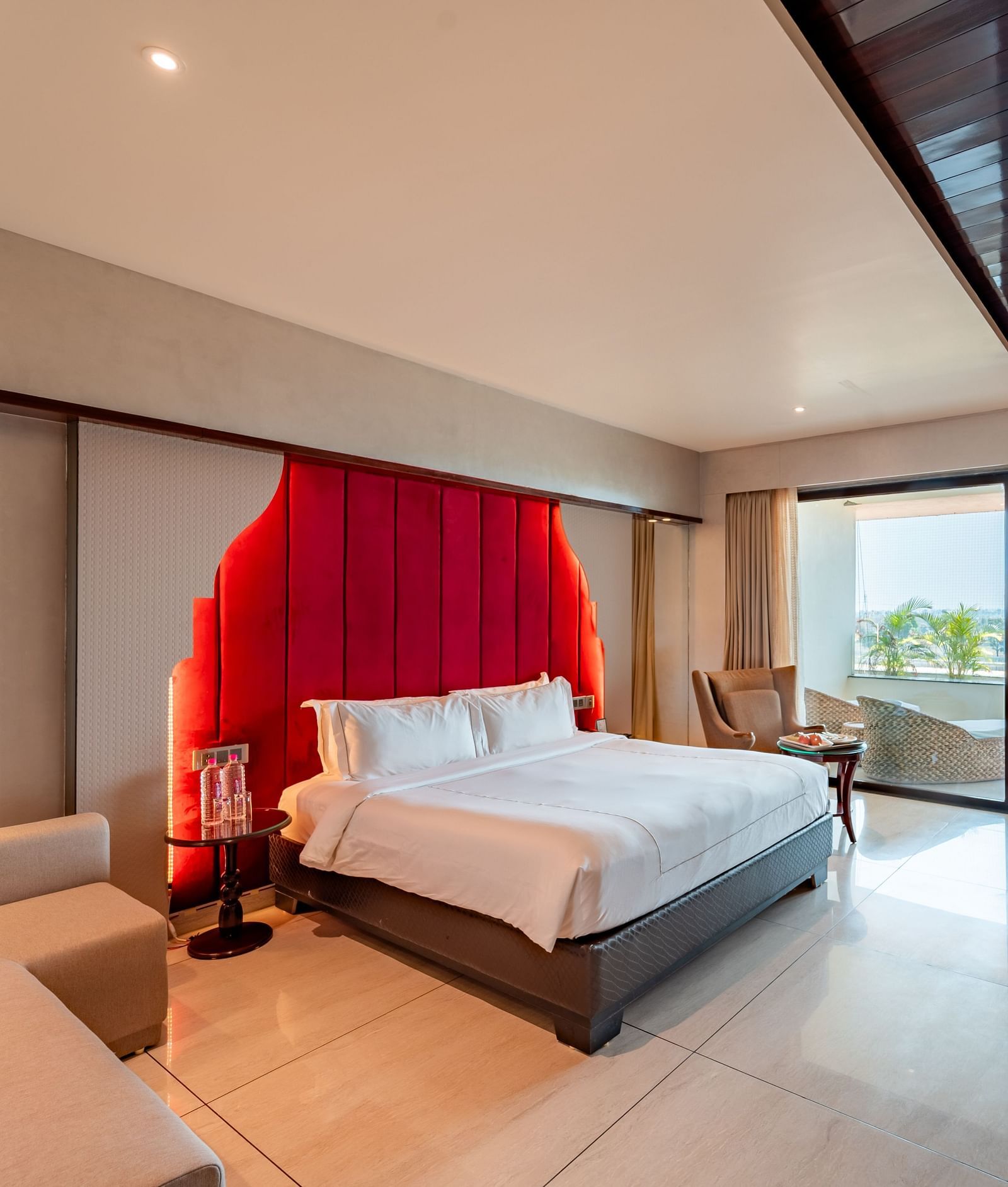 Executive Room features a spacious bed, cushioned sofa, wall-mounted television, and a large doorway leading to the balcony at Crescent Spa & Resort, Indore