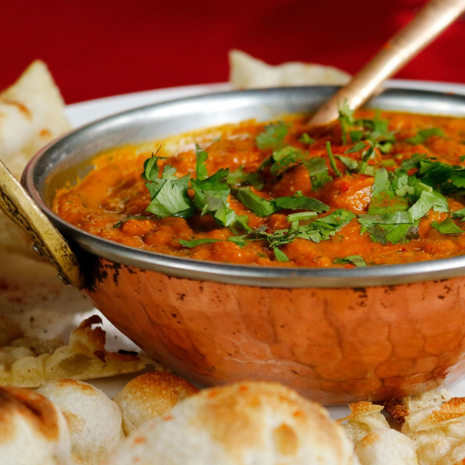 image of an indian preparation of paneer topped with chopped coriander leaves served with naan