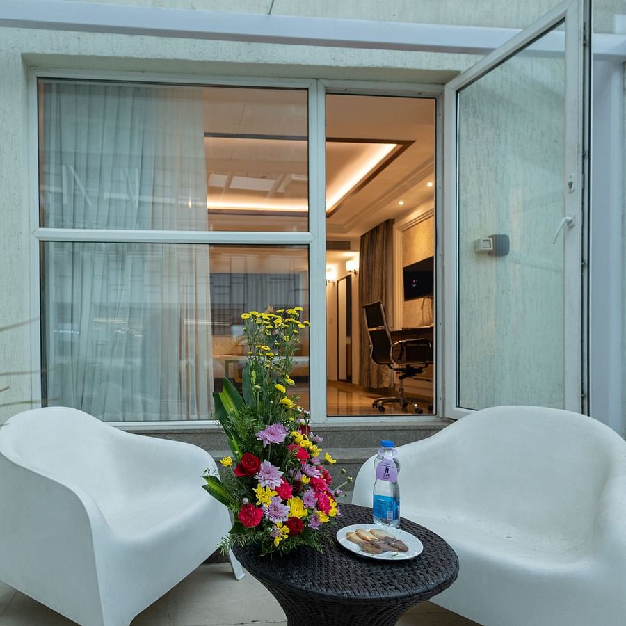 Balcony outside the executive room with two chairs, a table, and a flower bouquet at Icon Premier Hotel by Bhagini, Devarabisanahalli