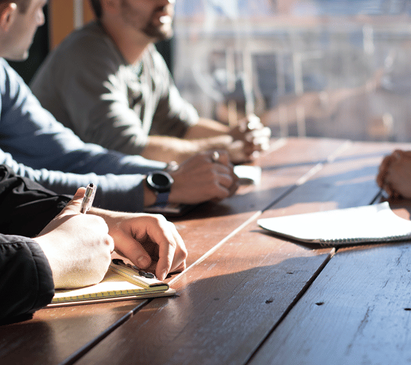 A business meeting in progress around a wooden conference table.