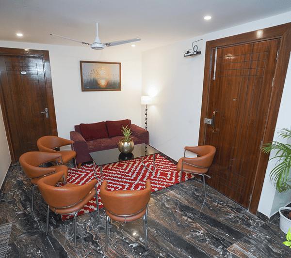 Lobby lounge with orange armchairs and a red sofa.