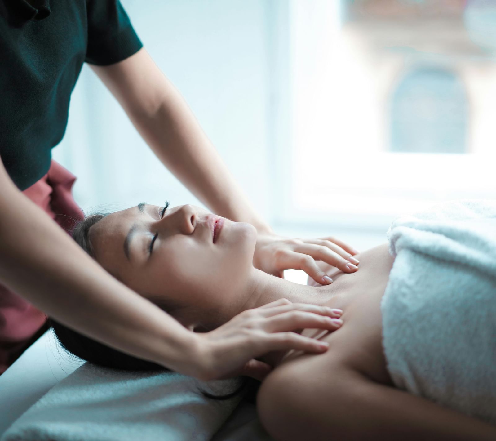 A woman receiving a relaxing shoulder massage by a masseuse.