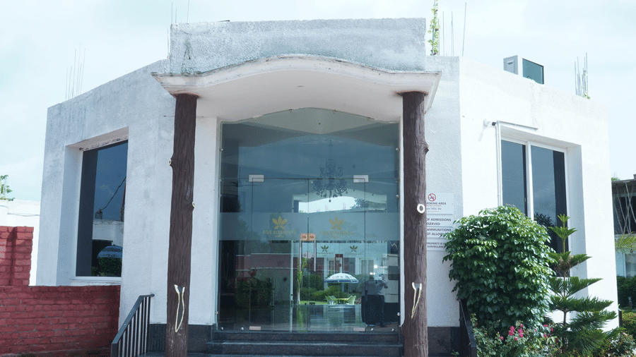 Exterior front entrance view of the hotel main building featuring large glass doors, steps, and surrounding landscape - Five Elements Hotels, Corbett Crown Resort, Jim Corbett