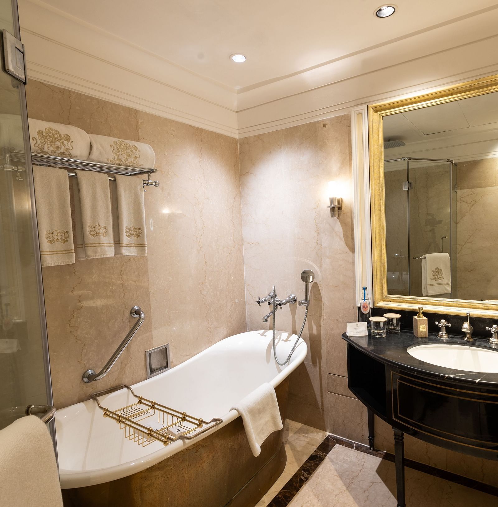 Grand Luxury Room washroom at The Claridges New Delhi, featuring a bathtub, a sleek sink, and a wall-mounted mirror