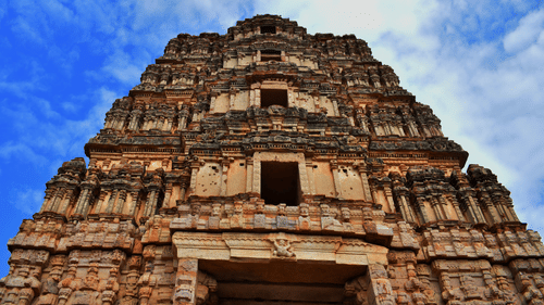 A stunning low-angle shot of a temple with intricate architecture set against the backdrop of a cloudy sky - Hotel near Tirupati temple