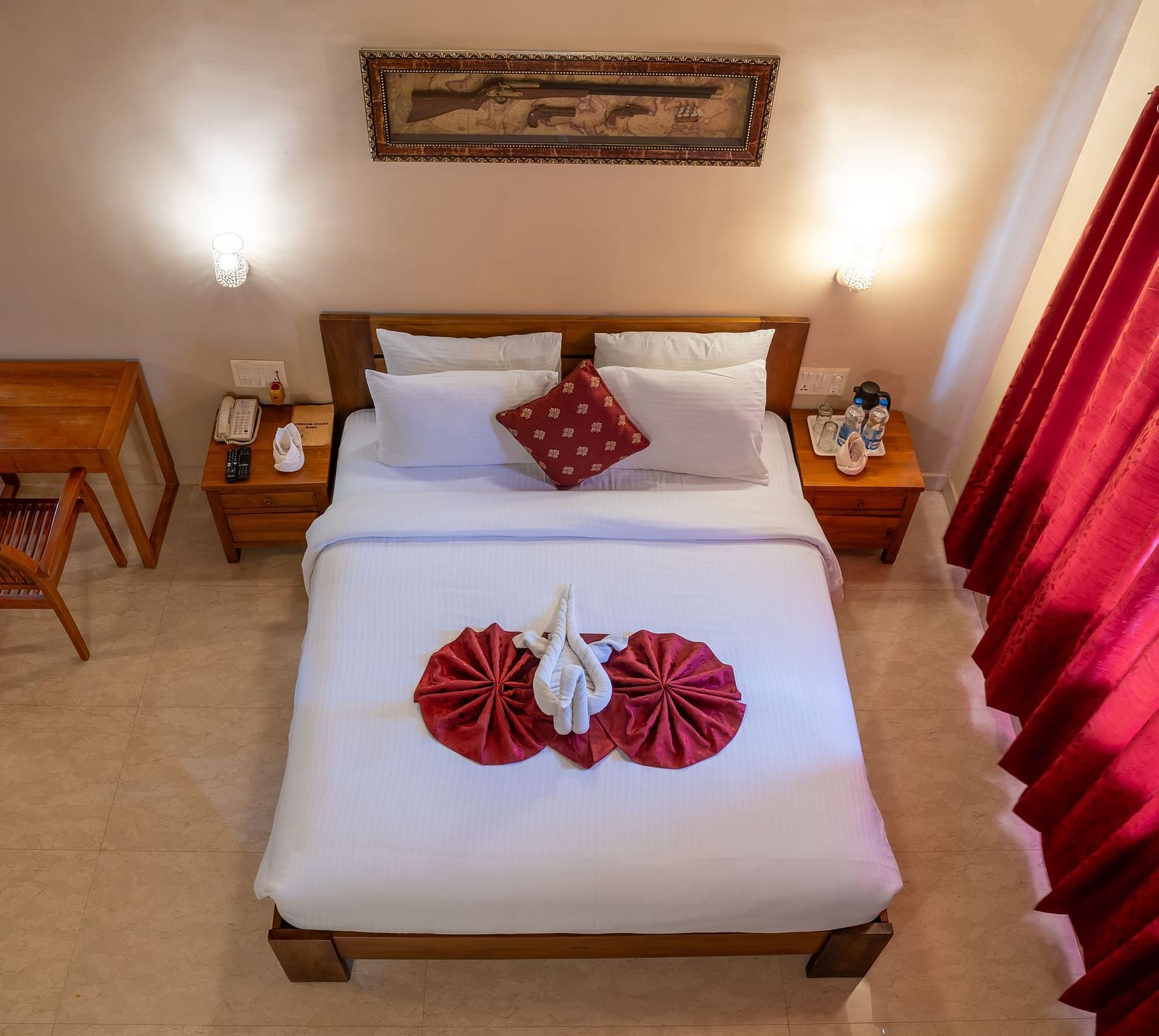 A top-down view of Attic Villa shows a simple king size bed with red accents and clean white linens | Woodstock Resorts, Coorg