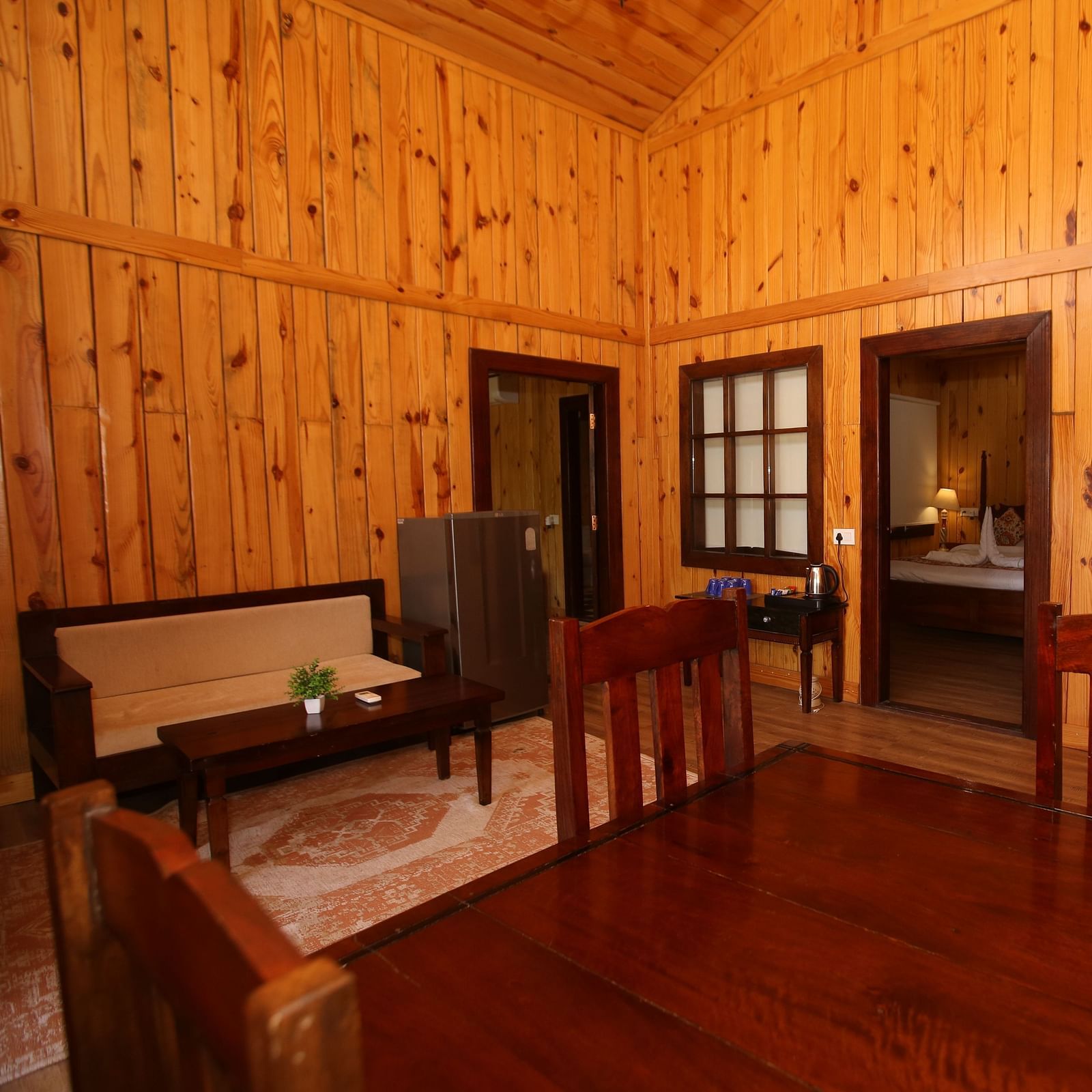 Cozy corner seating in Kashmir Cottage Villa's Pool room, featuring a sofa, chair, and stylish wooden flooring at Aanandam Resort & Spa