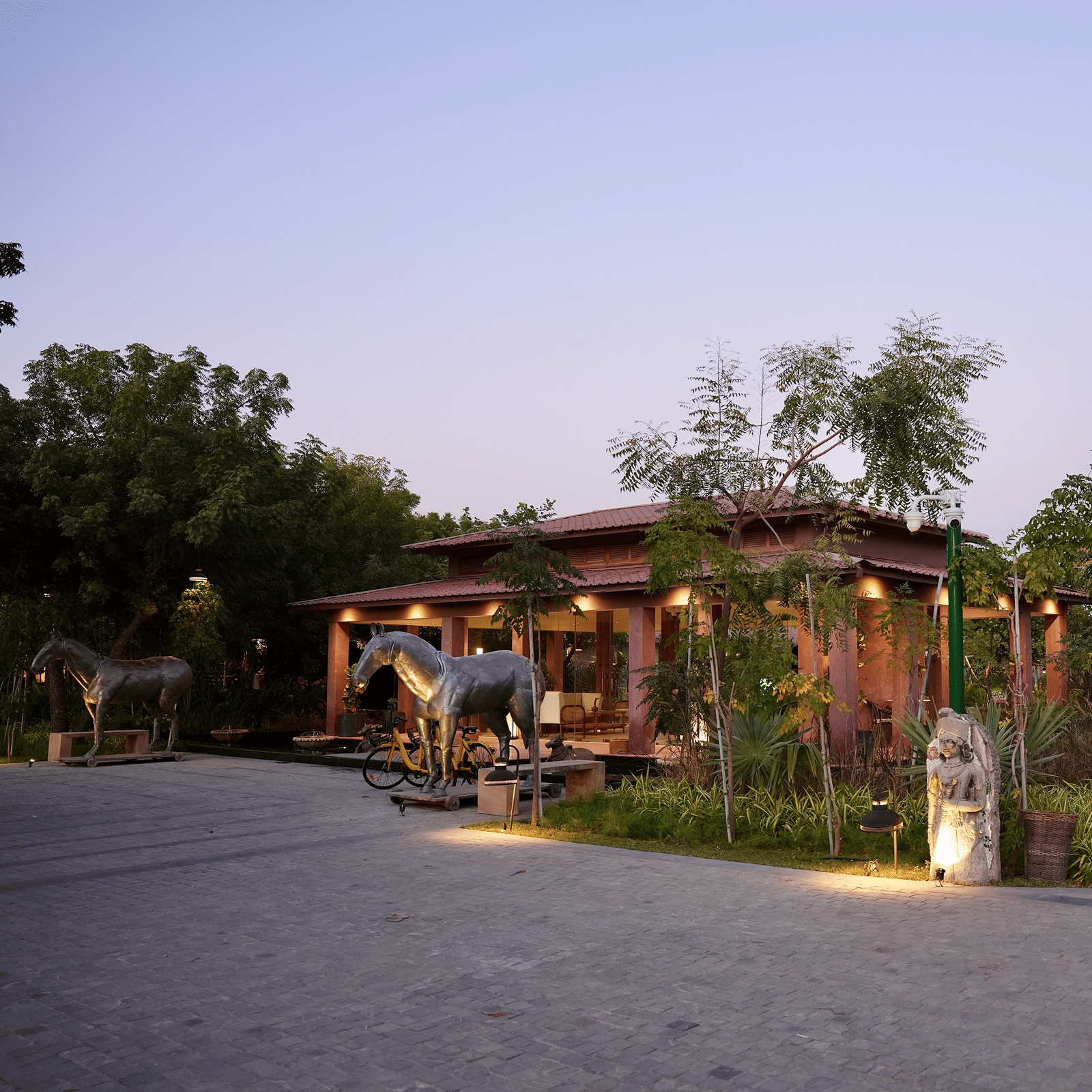Facade of Surpura Bagh with trees surrounding it and a pathway leading to the reception under evening sky
