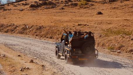 An open-top safari gypsy driving along a dusty dirt track during a wildlife safari in Ranthambore.