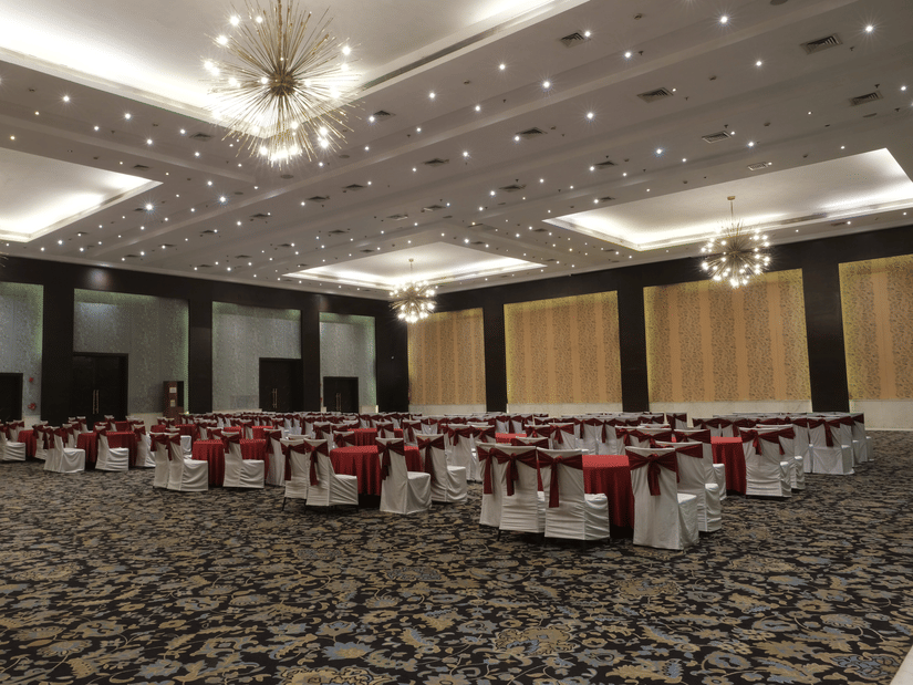 The spacious Clarks Brij Convention Centre featuring statement chandeliers, elegant seating arrangements, and a refined setting prepared for a large wedding celebration or reception | Clarks Amer, Jaipur