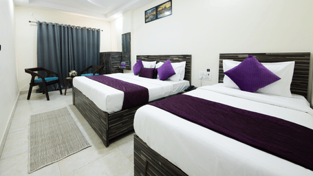A bedroom with 2 king size beds, a television, a ceiling fan, side tables, 2 chairs, and a cabinet at Perfectstayz Value Umra Grace, Haridwar