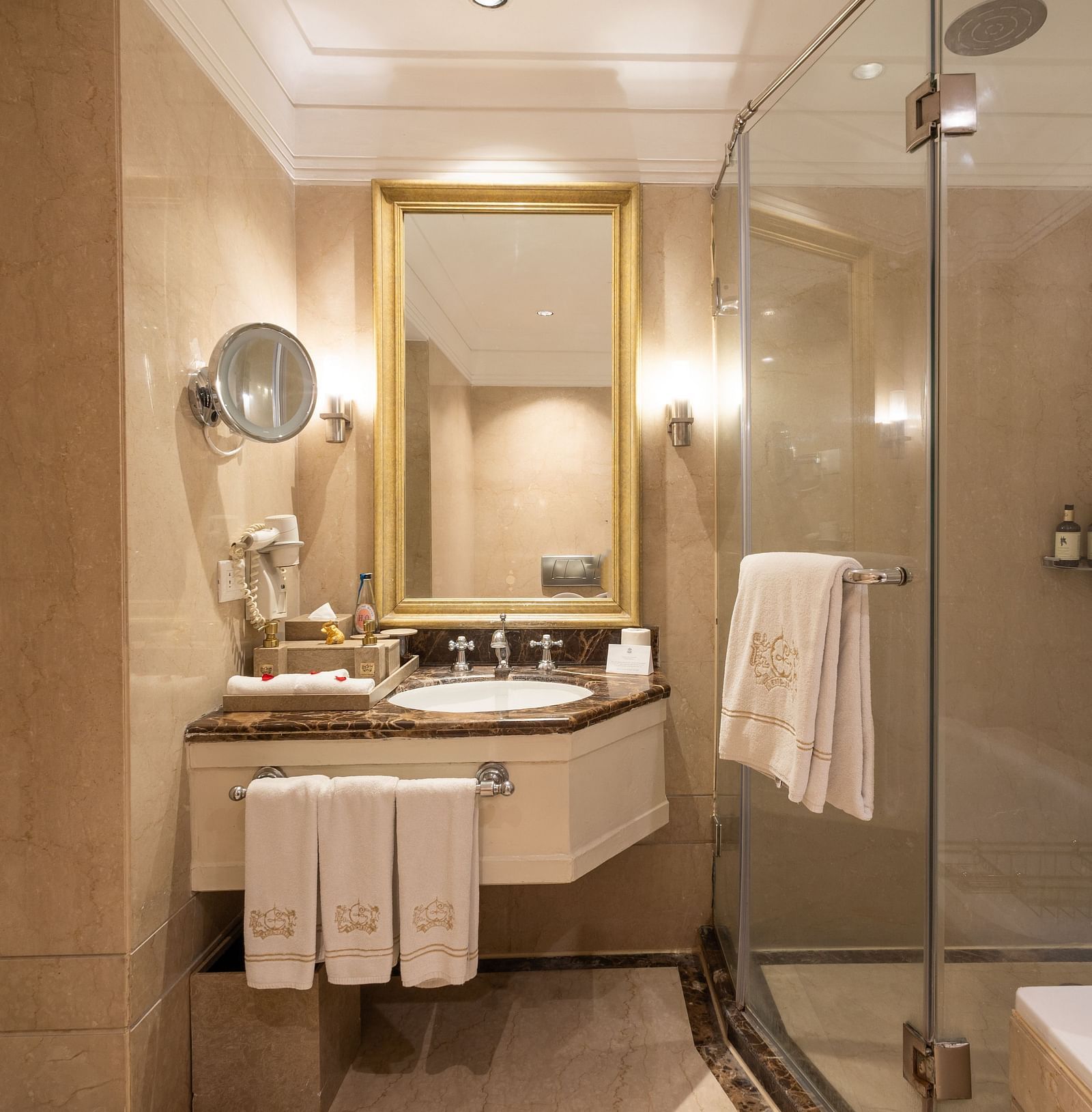 Washroom of the Grand Luxury Twin Bed Room at The Claridges New Delhi, featuring a modern sink, a wall-mounted mirror, and a glass-enclosed bath area