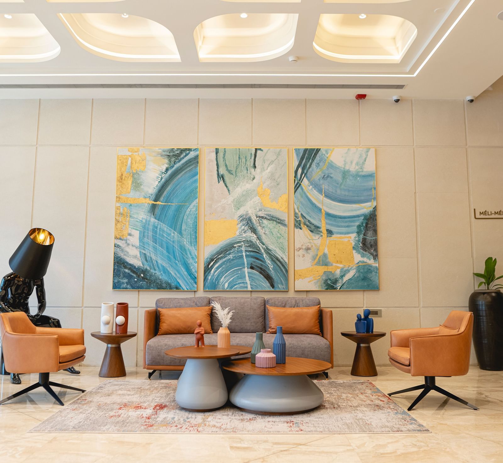 Lobby at KertelSuites, featuring a cosy sofa, a round coffee table, and an elegant ceiling with stylish lighting.