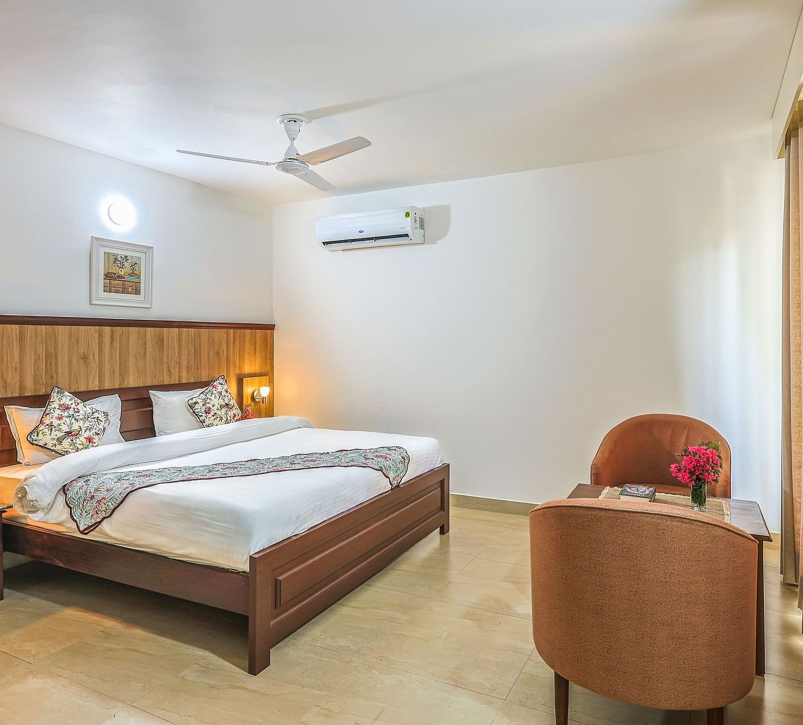 a double bed with side tables, lamps and chairs opposite it inside one of the rooms - Neer ganga Resorts