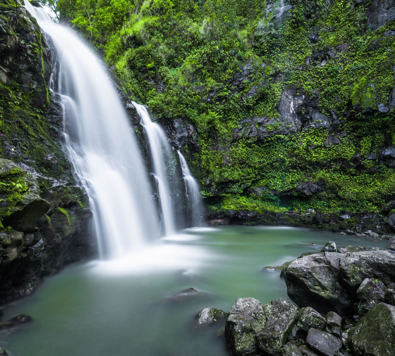 a waterfall cascading down to a waterbody with trees on either side