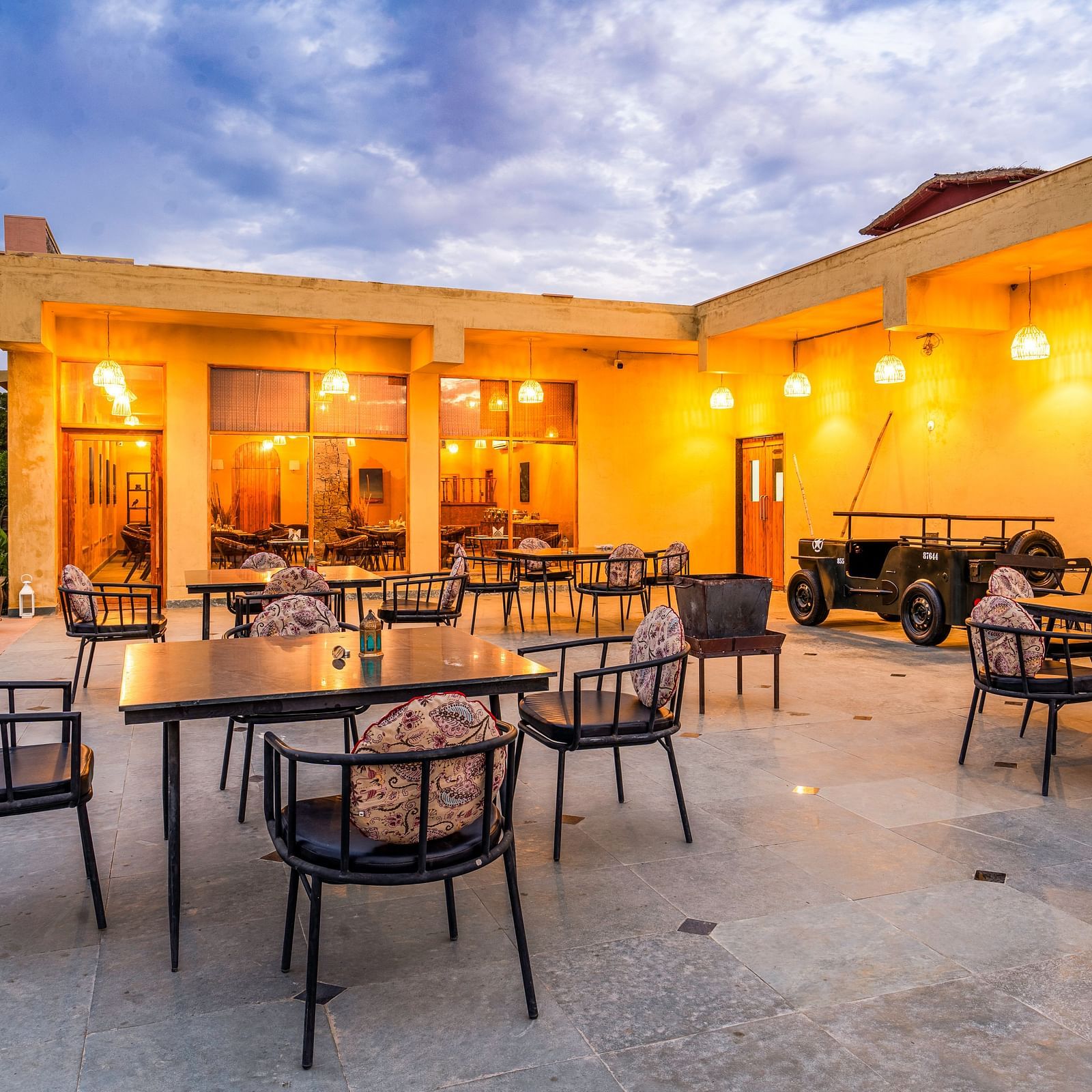 An image of rosettes restaurant featuring several lamps hanging from the roof and various sets of  tables and chairs are placed both indoor and outdoor at Kurja Jawai