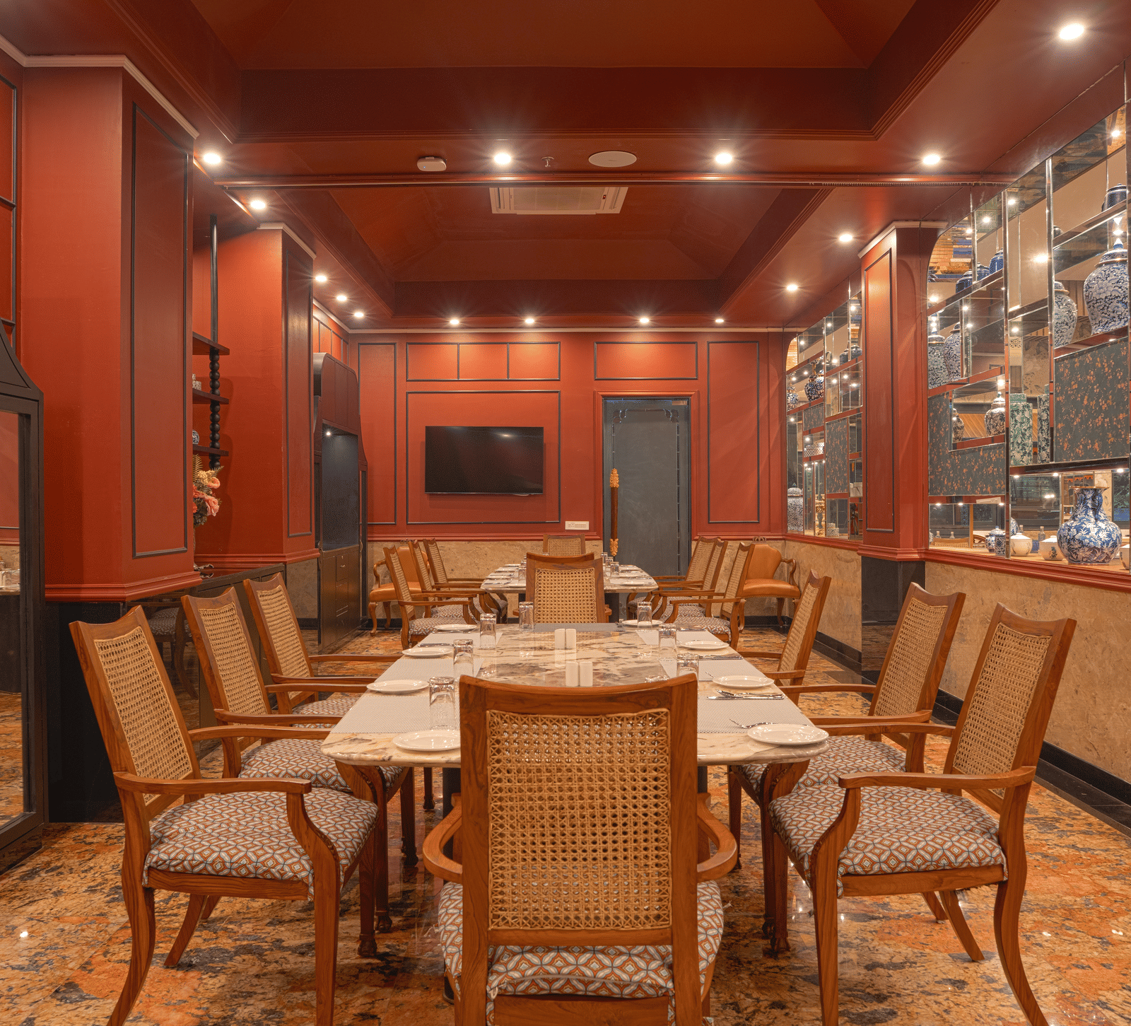 A dining room with a long wooden table set for a meal, surrounded by upholstered chairs and wood-panelled walls at MAYFAIR Bay Resort, Paradeep.