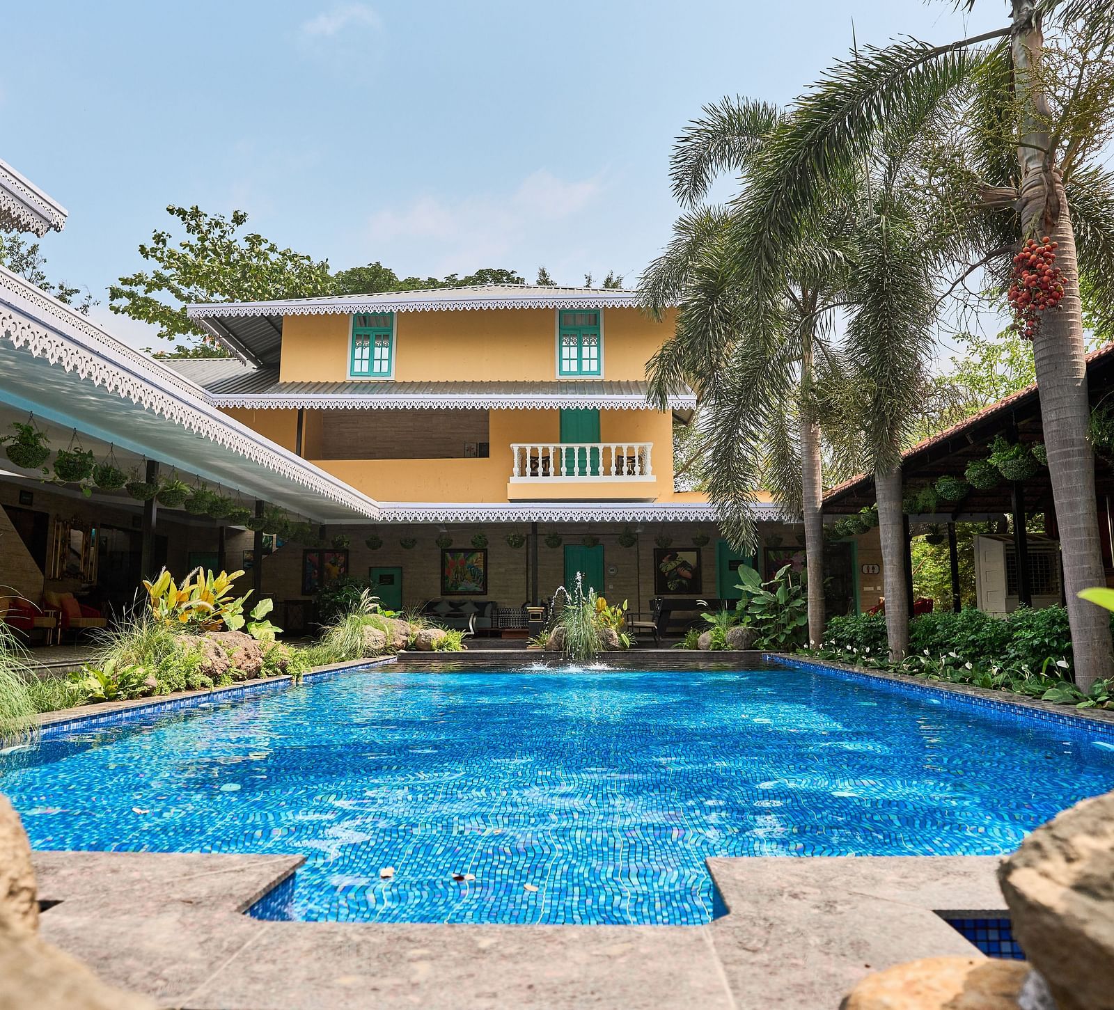 Swimming pool with a facade, surrounded by plants and trees at Mayfair Manor, Alibag