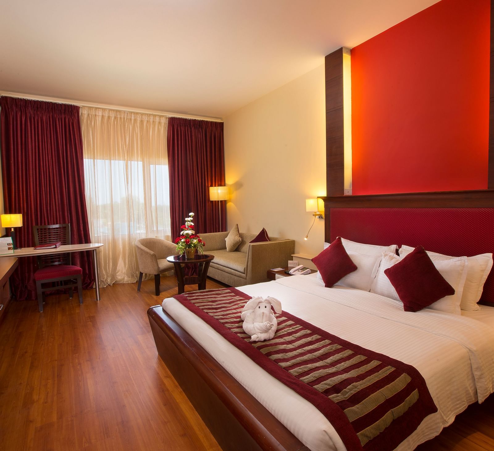 A well-appointed room with a comfortable bed, seating areas, a TV, and lamps.