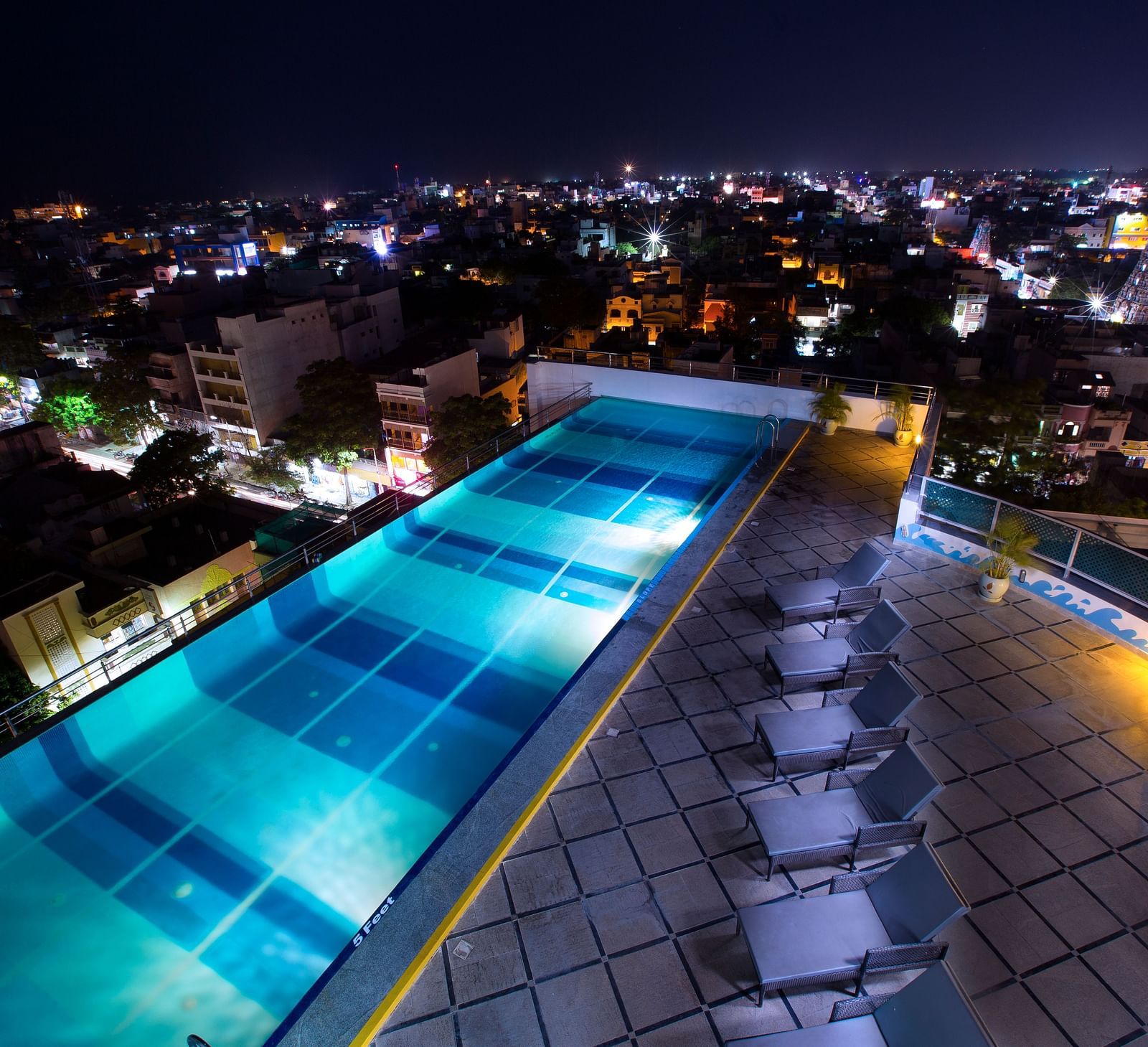 Rooftop Pool with lounging chairs during the night at Hotel Atithi - TGI Grand, Pondicherry