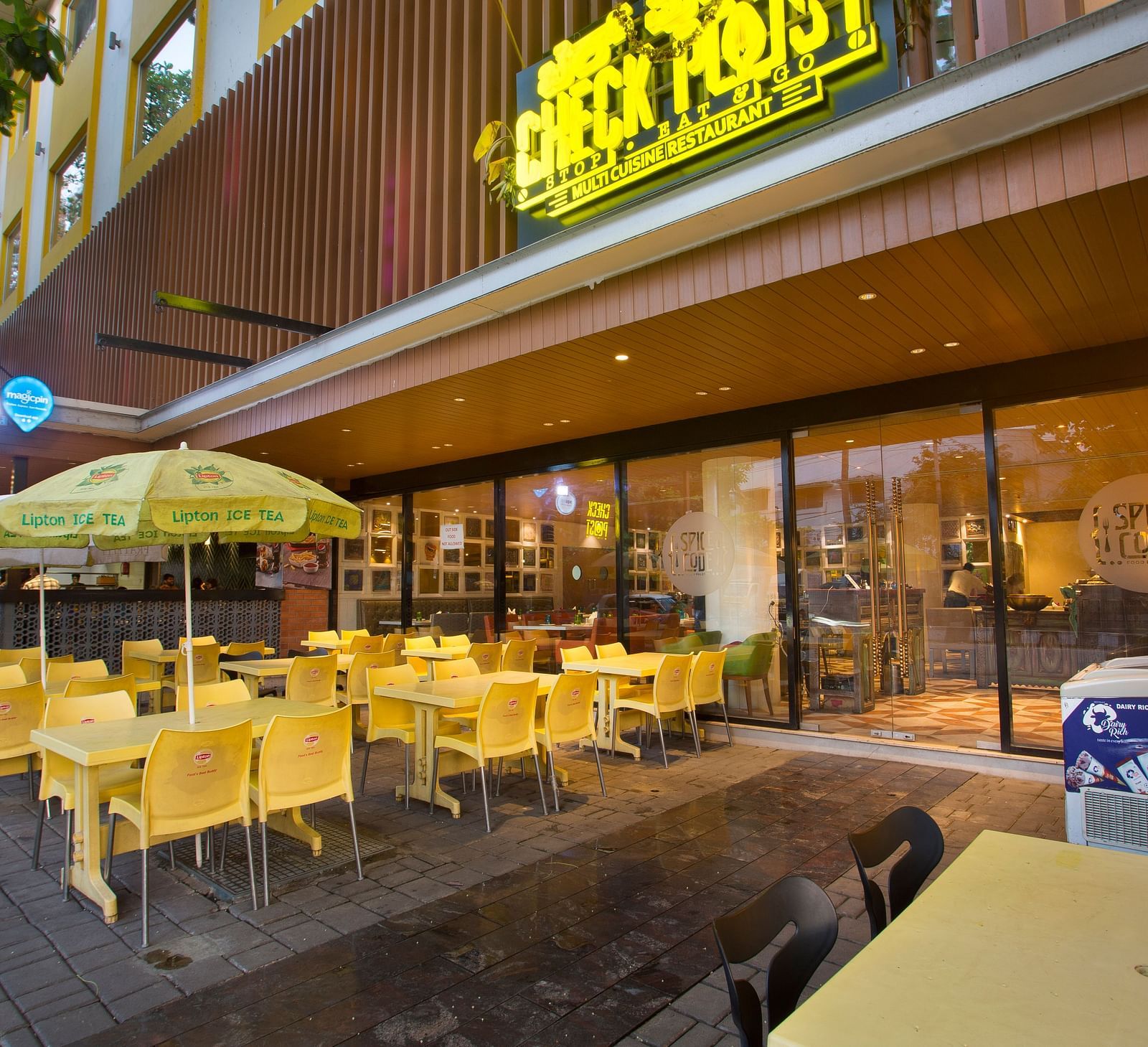 an outdoor restaurant with umbrellas mounted on the tables to provide shade - Hotel Fountain Tree By TGI - JP Nagar, Bangalore