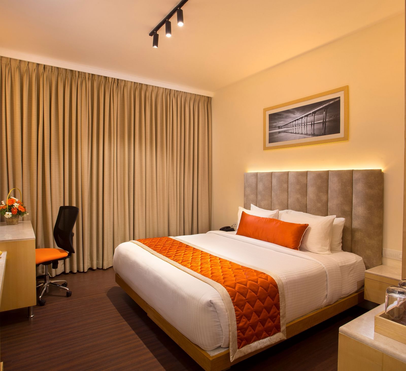 A cosy hotel room with a plush bed adorned with an orange bed runner, a work desk and a wall-mounted TV - Hotel Langford Keys by TGI, Shanti Nagar