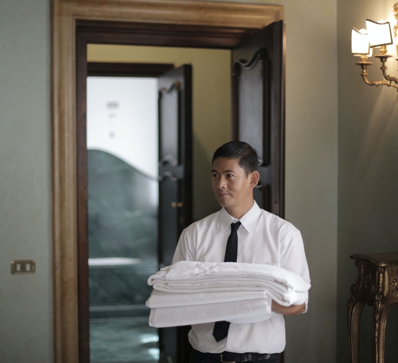 A hotel attendant carrying a stack of fresh white towels