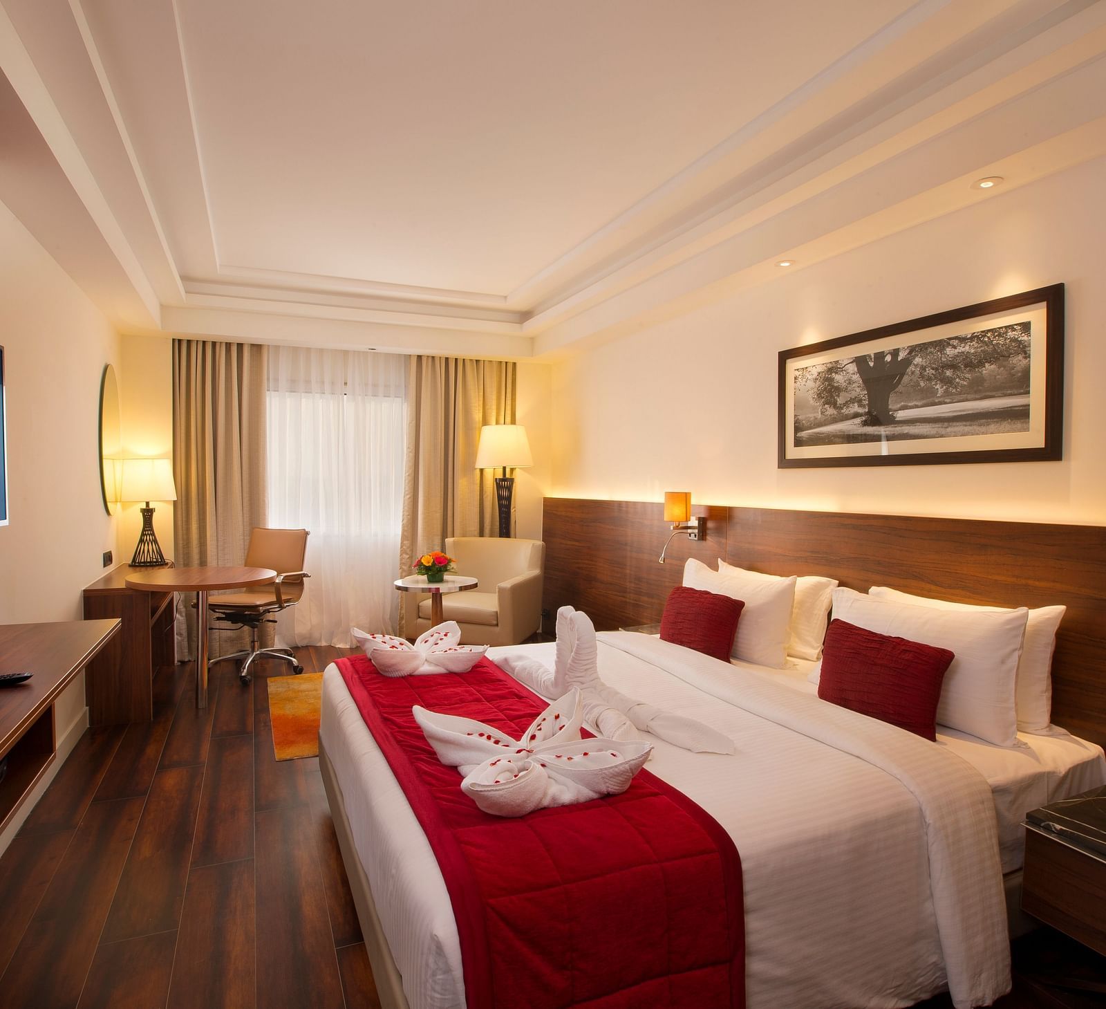 An elegant hotel room with a large bed, red throw blanket, decorative pillows and a framed black-and-white photograph on the wall - Hotel Southend by TGI - Bommasandra, Bangalore