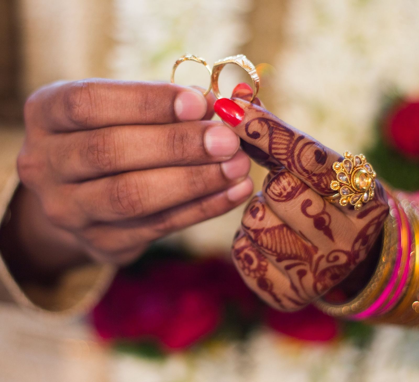 A close-up of a people's hands exchanging wedding rings