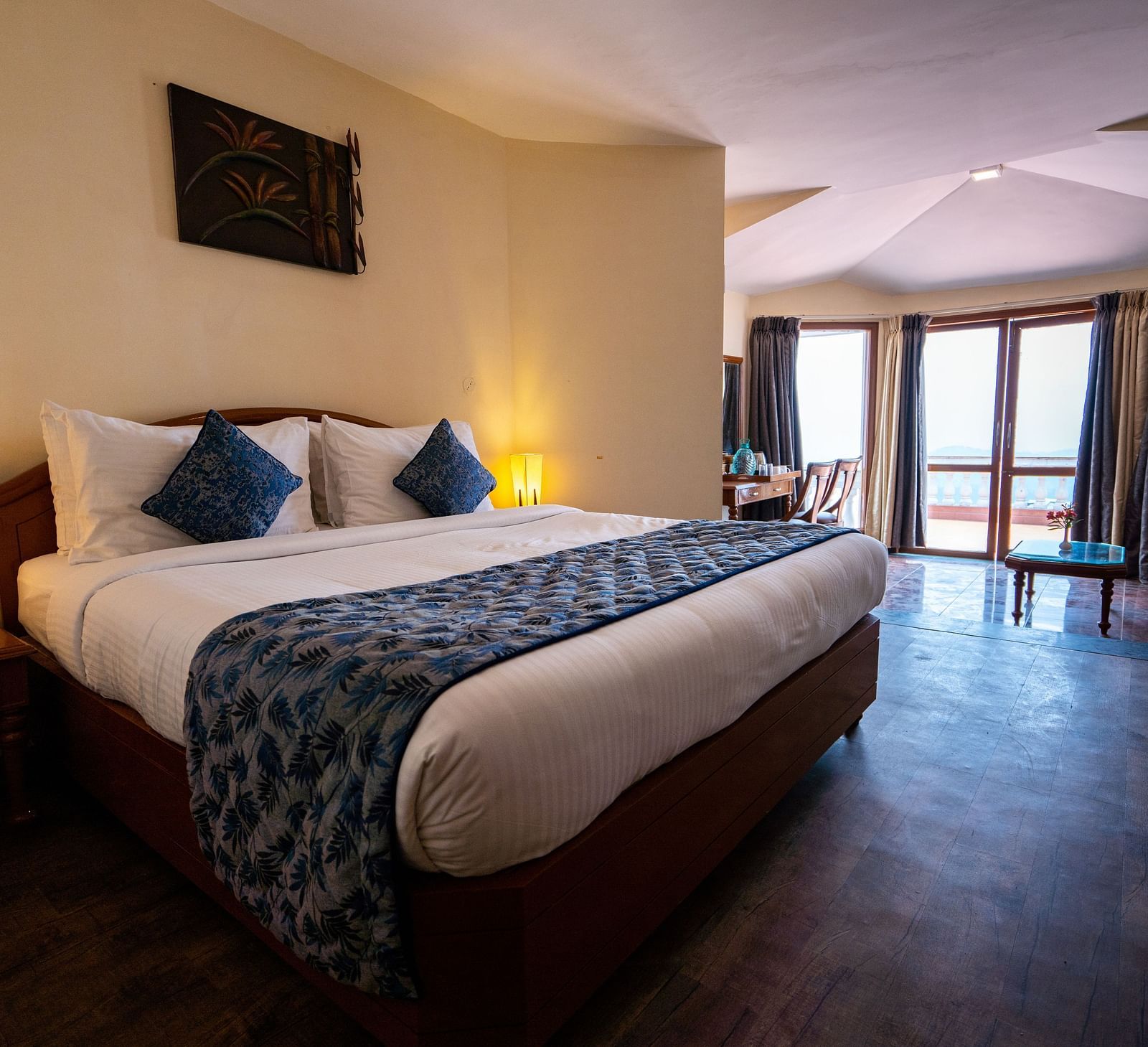 comfy bed with blue duvet and pillows at La Montana By TGI, Ooty