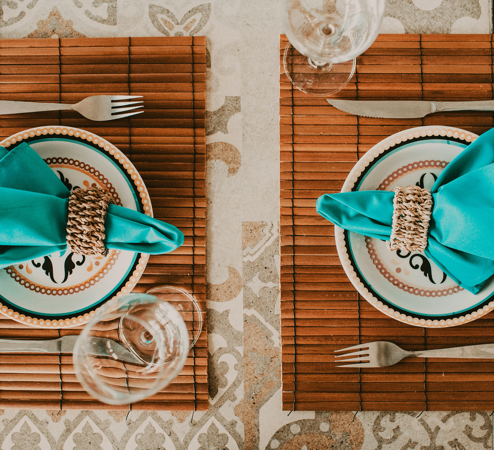 An image of a restaurant table with plates, cutlery, and glasses laid on it