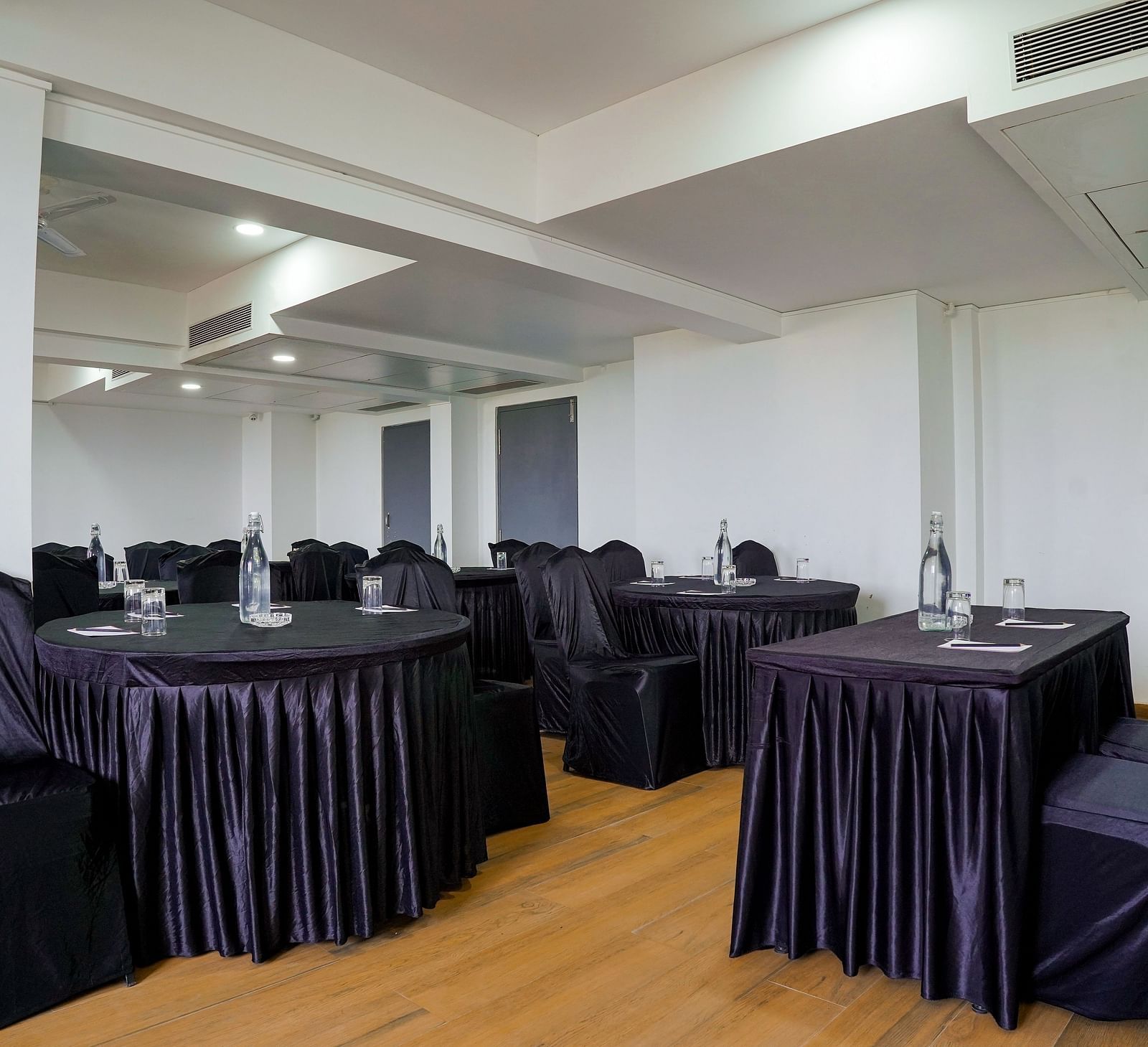 Spacious conference room with round tables and chairs covered in black - TGI Ameya Grand, Goa