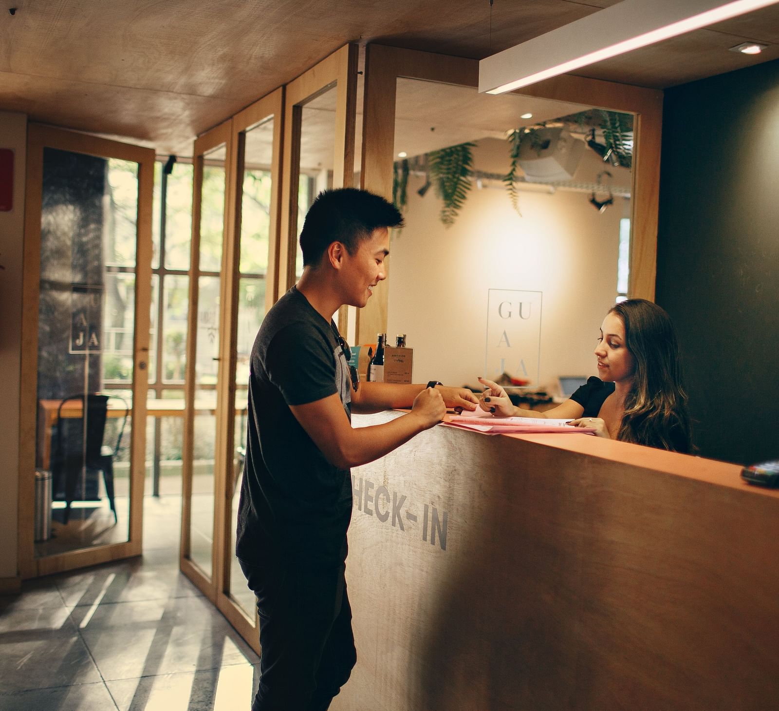 A young man checking in at a hotel reception desk with a female receptionist