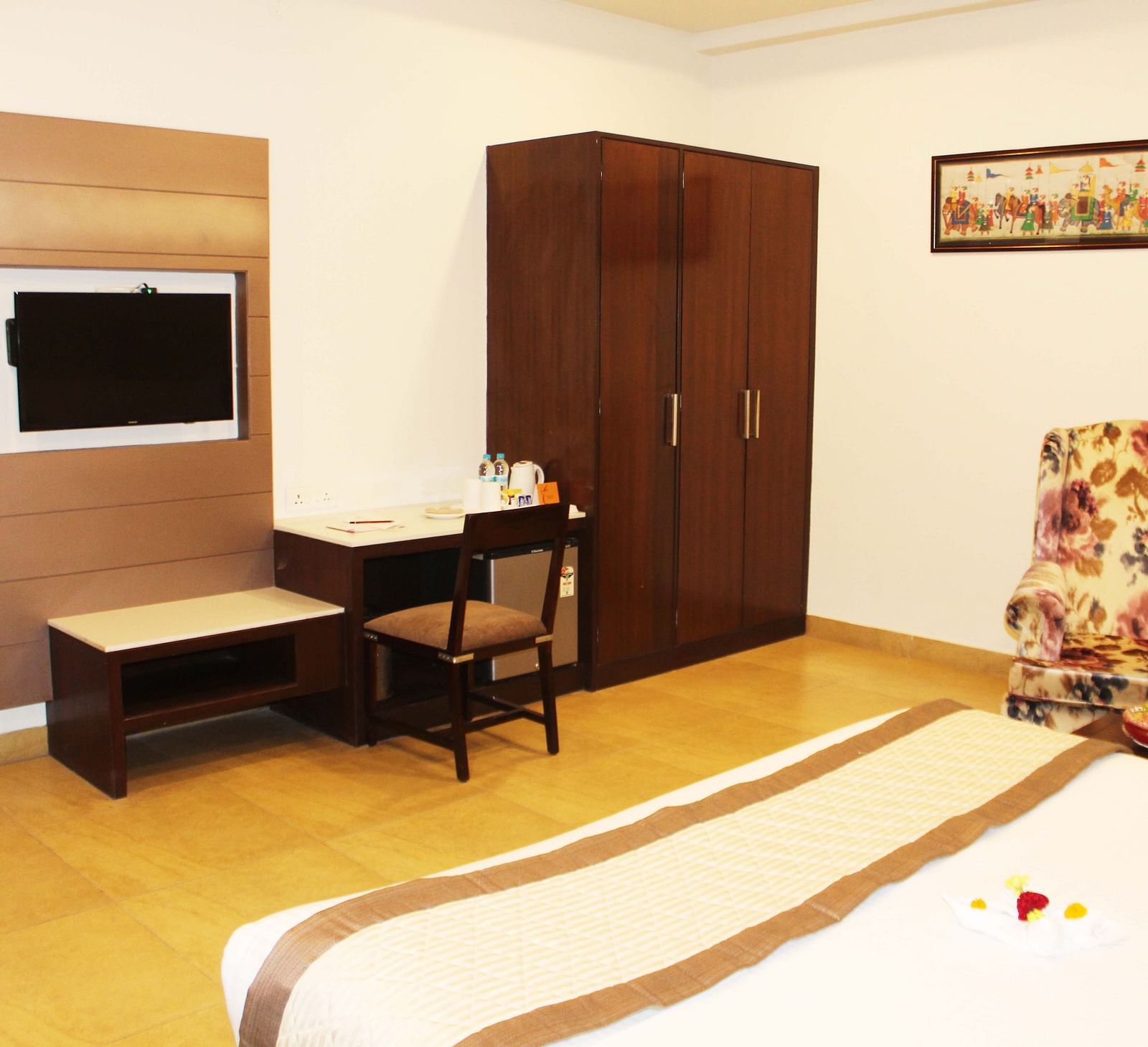 A view of the suite with a comfortable bed, a relaxing chair, a flat TV and furniture - TGI Apple Inn, Jaipur 