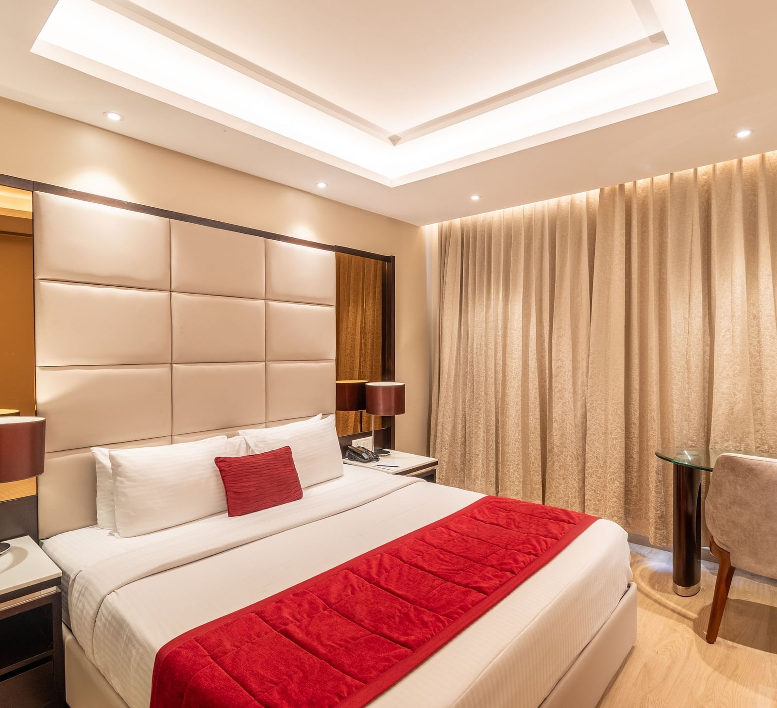 Fortuna suite's bedroom with full-length curtains, bedside table, and armchair- TGI Grand Fortuna, Krishnagiri Main Road, Hosur