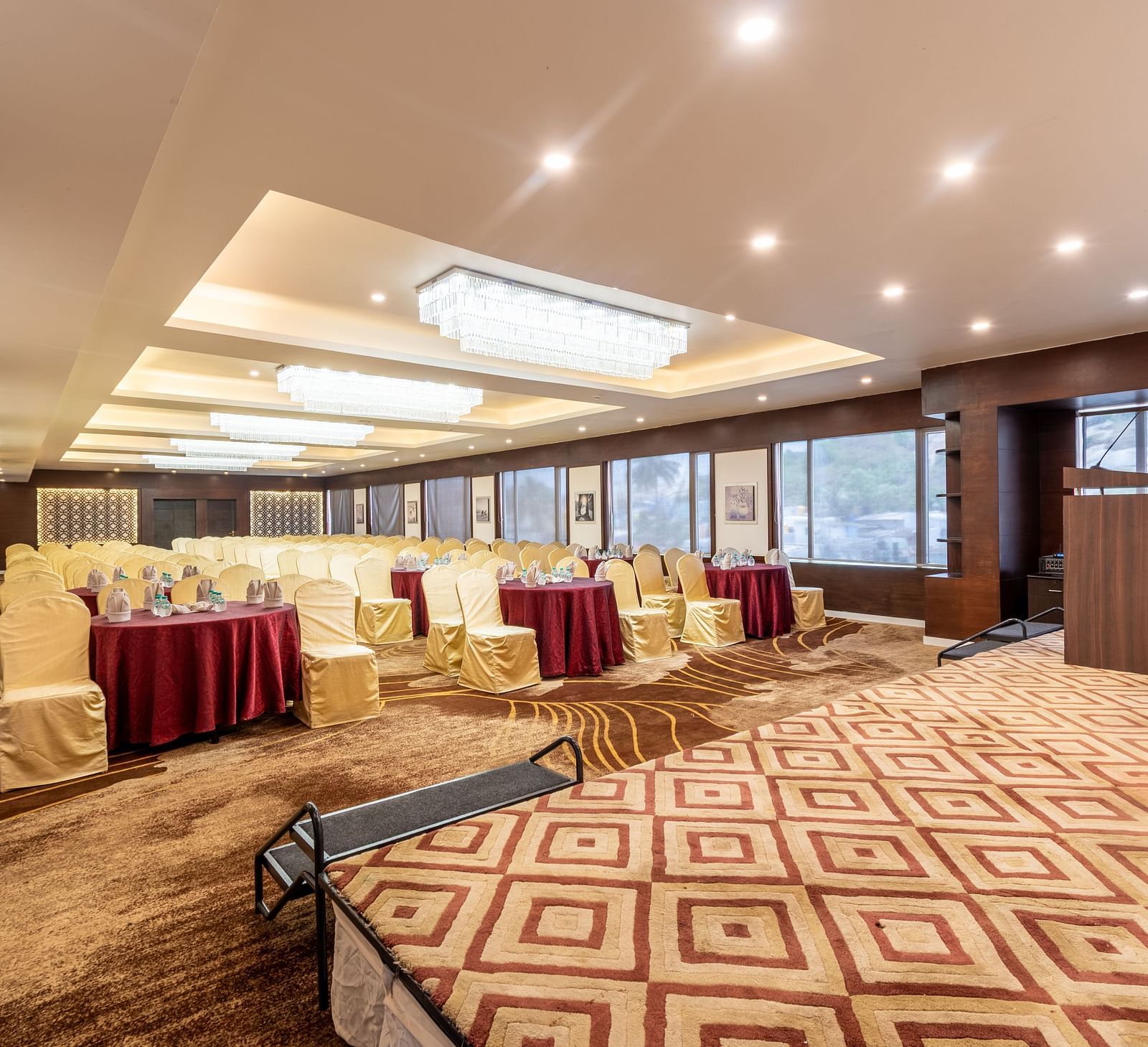 Versatile banquet space with podium and large windows, set for a business meeting or seminar