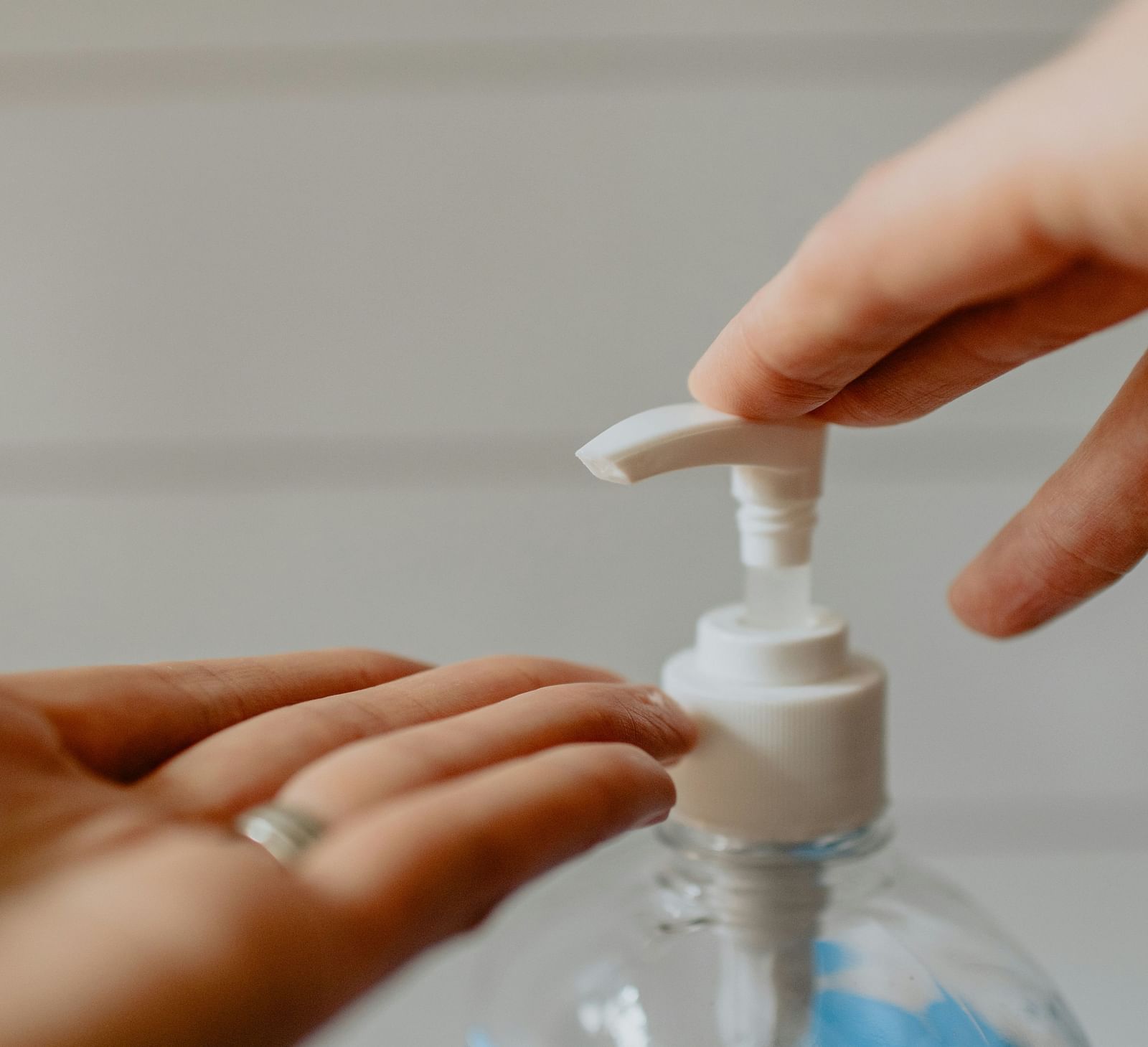 A person dispensing liquid from a bottle with a pump dispenser