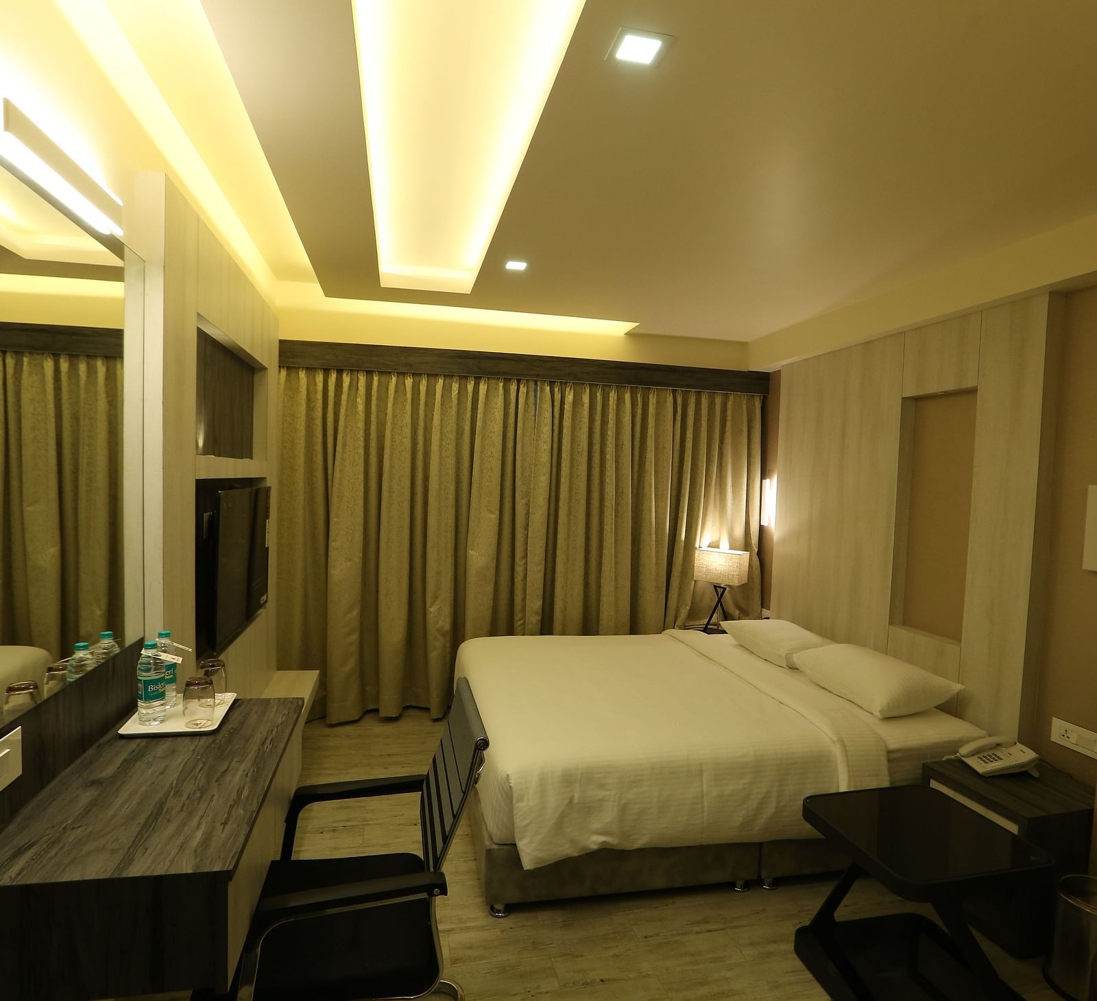 Premium Room featuring a king size bed, desk with a mirror, chair, and ambient lighting, showcasing the room's layout and decor - TGI SPS Grand, Coimbatore